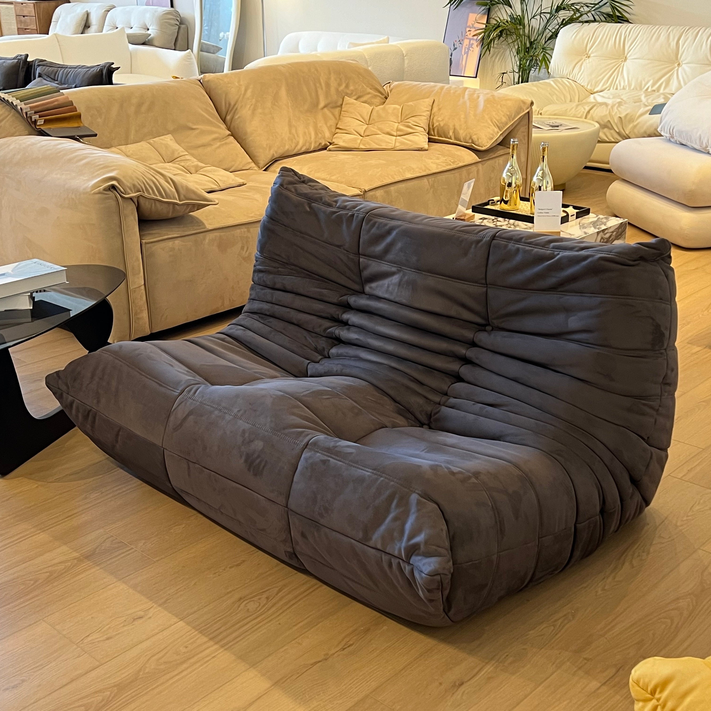 The sofa's design features unique horizontal folds and a plush, velvety texture, offering a stylish and comfortable seating option.