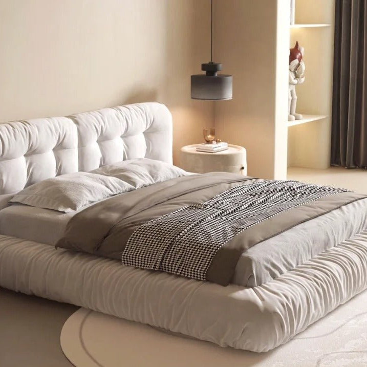 Italian-style cloud bed in ivory suede fabric, displayed in a beige modern bedroom with a carpet under it.