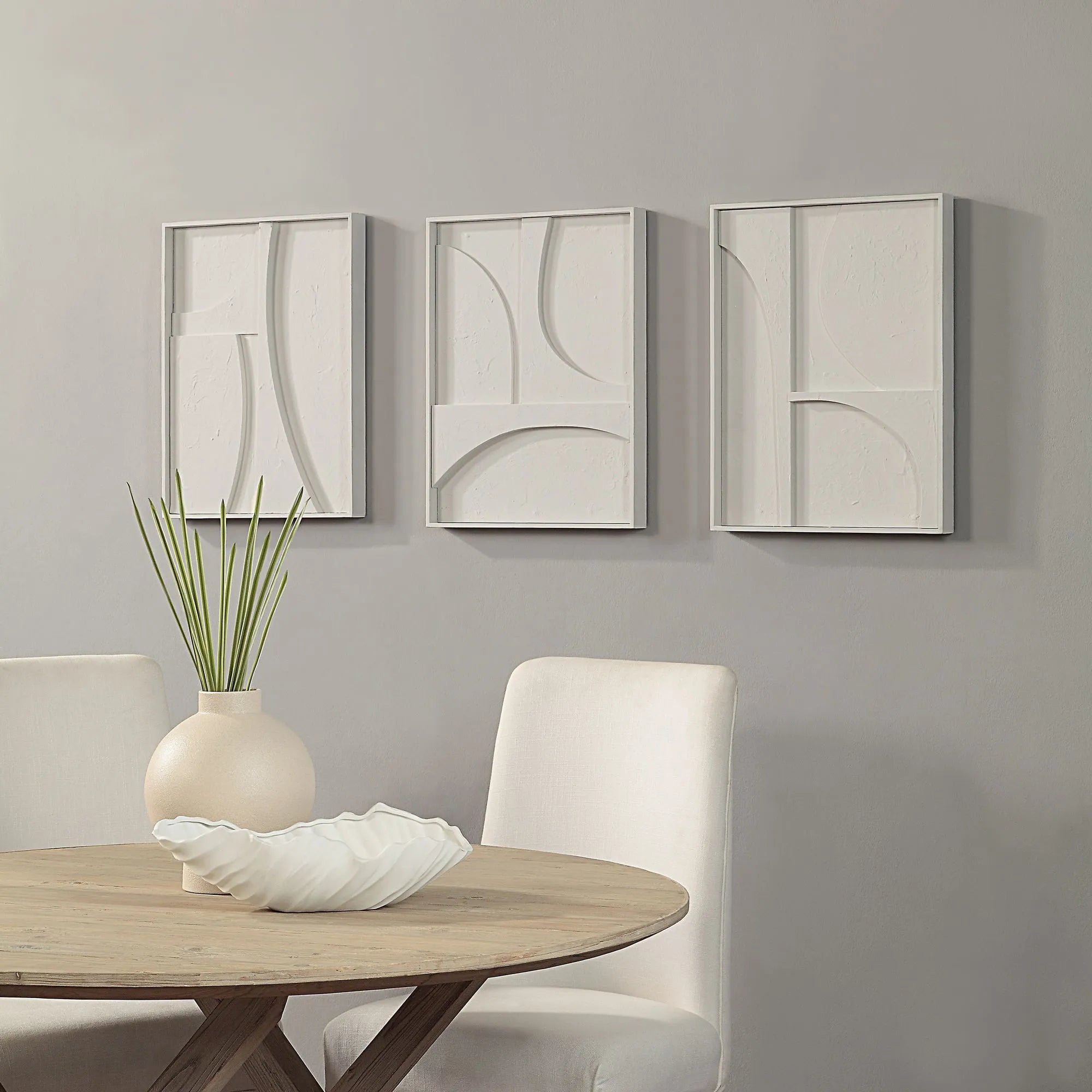 Arcus Relief wall art set displayed in a styled dining space with sculpted white panels mounted on a soft grey wall