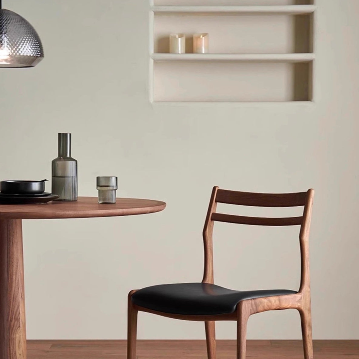 Aspen Classic Dining Chair with walnut frame and black cushioned seat shown beside a round wooden dining table