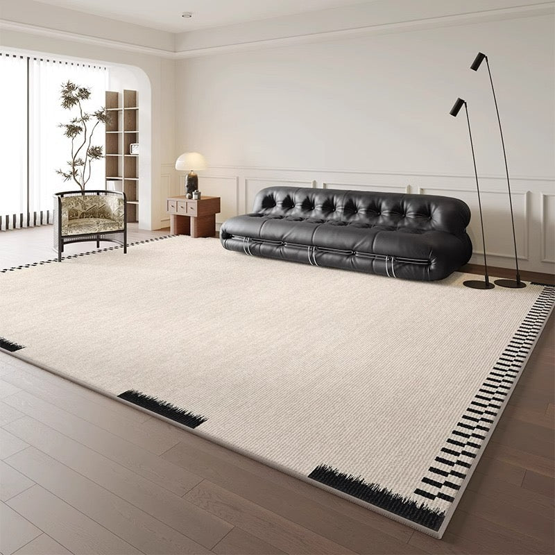 Atelier Border Area Rug styled in a modern living room with black sofa and corner pattern accents
