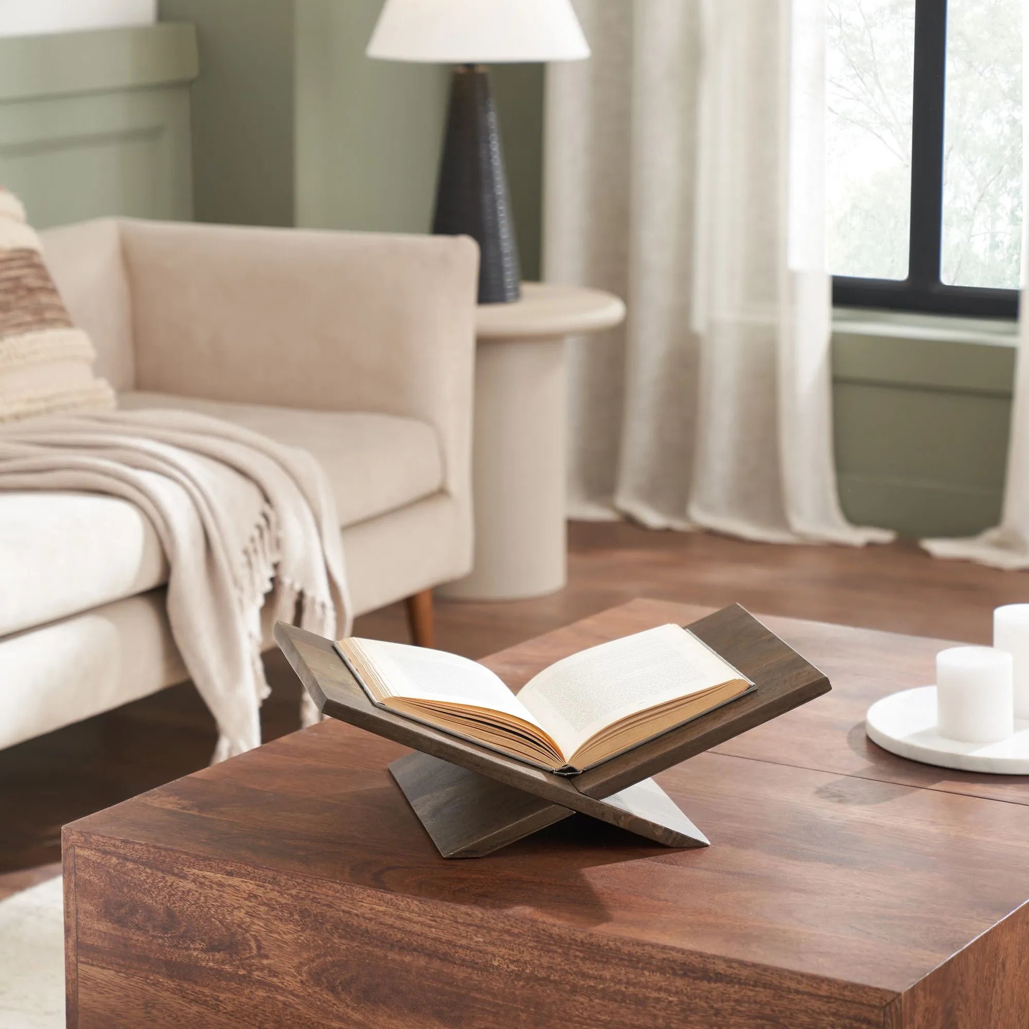Atlas Walnut Book Stand styled on wooden coffee table holding open book in cozy living room setting