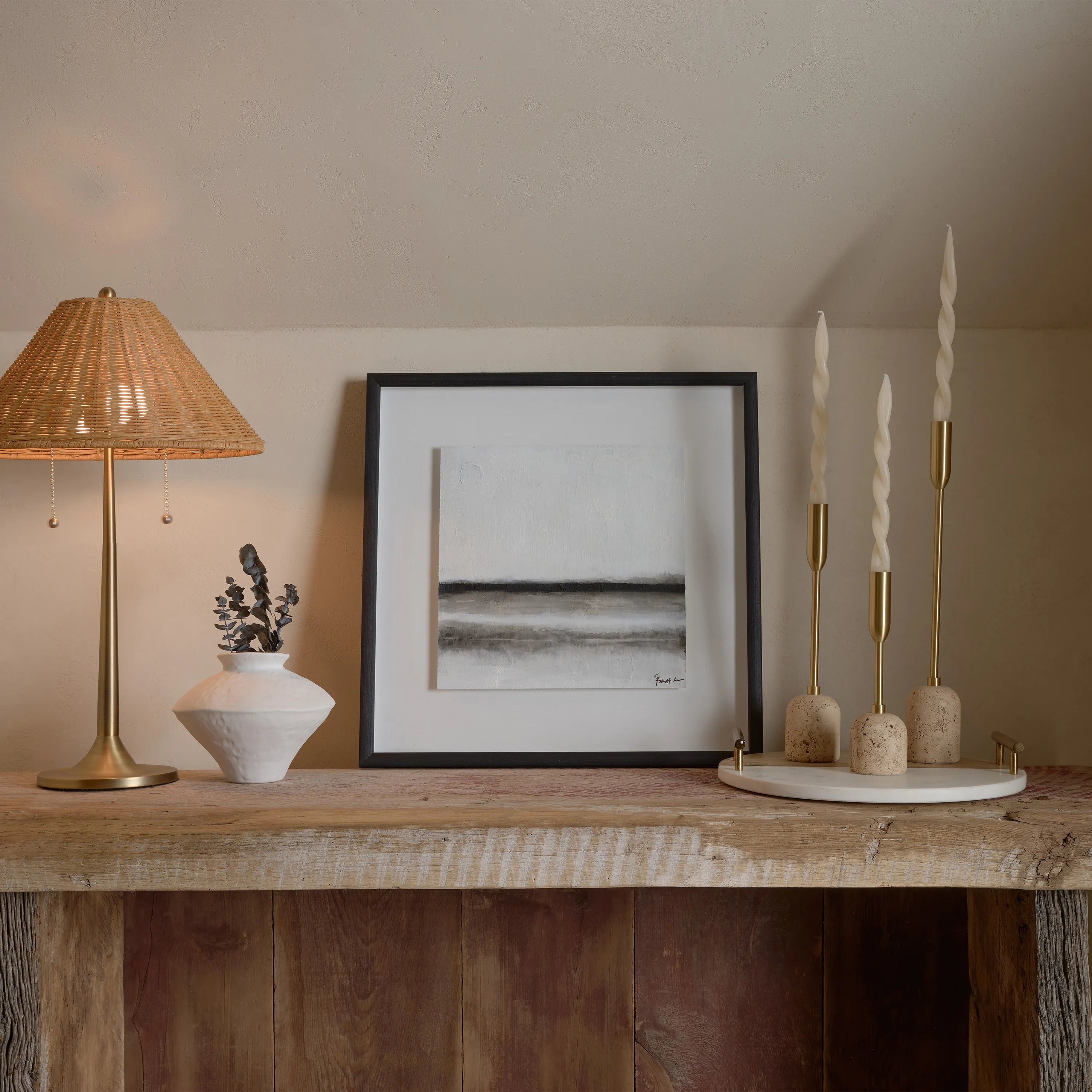 Aurelia Candle Holders displayed on a rustic wood mantel beside a rattan lamp, ceramic vase, and framed artwork