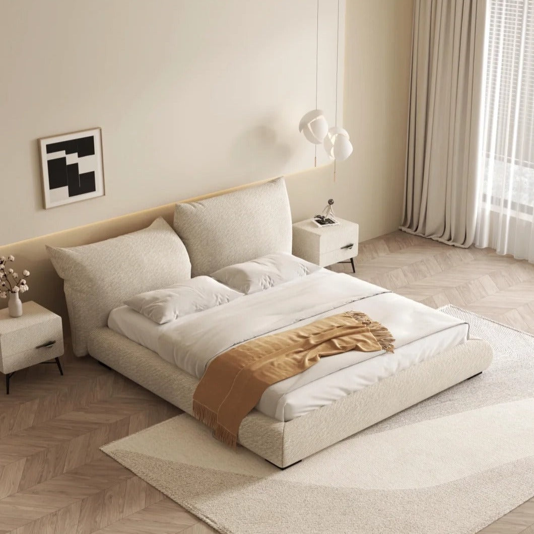 A contemporary bedroom setting featuring a beige upholstered bed frame with a low-profile design, accompanied by nightstands and a headboard.