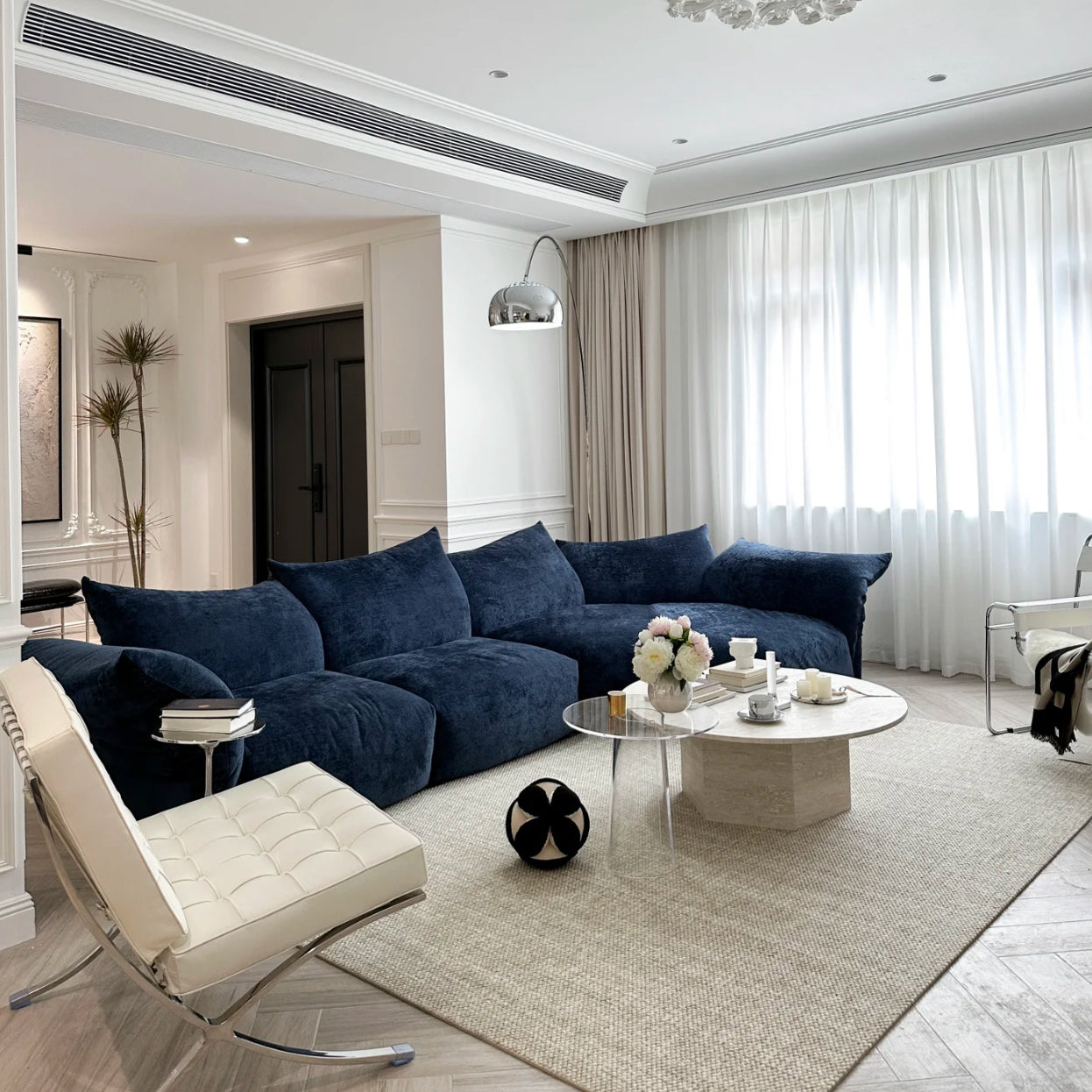 Blooming Embrace Modular Sofa in navy blue fabric styled in a modern living room with white walls, marble coffee table, and soft lighting