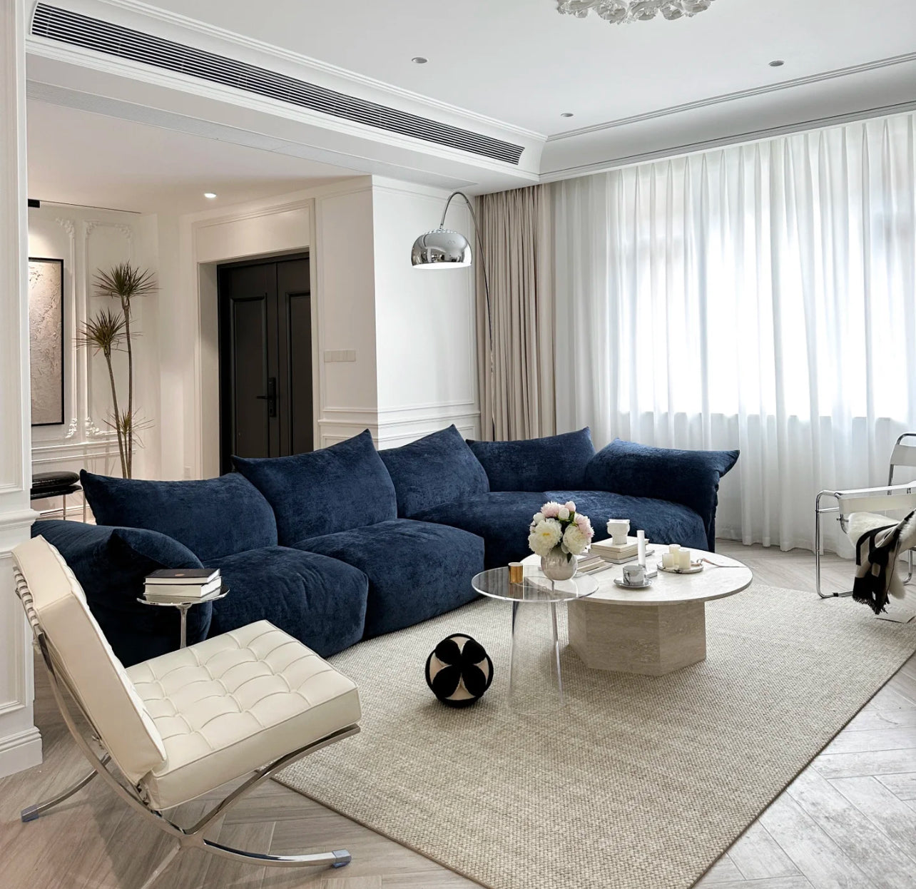 Blooming Embrace Modular Sofa in navy blue fabric styled in a modern living room with white walls, marble coffee table, and soft lighting
