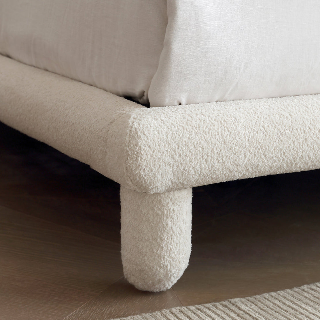 Close-up of Bubbly Bliss Bed leg showing soft white boucle upholstery and rounded frame detail on wooden floor