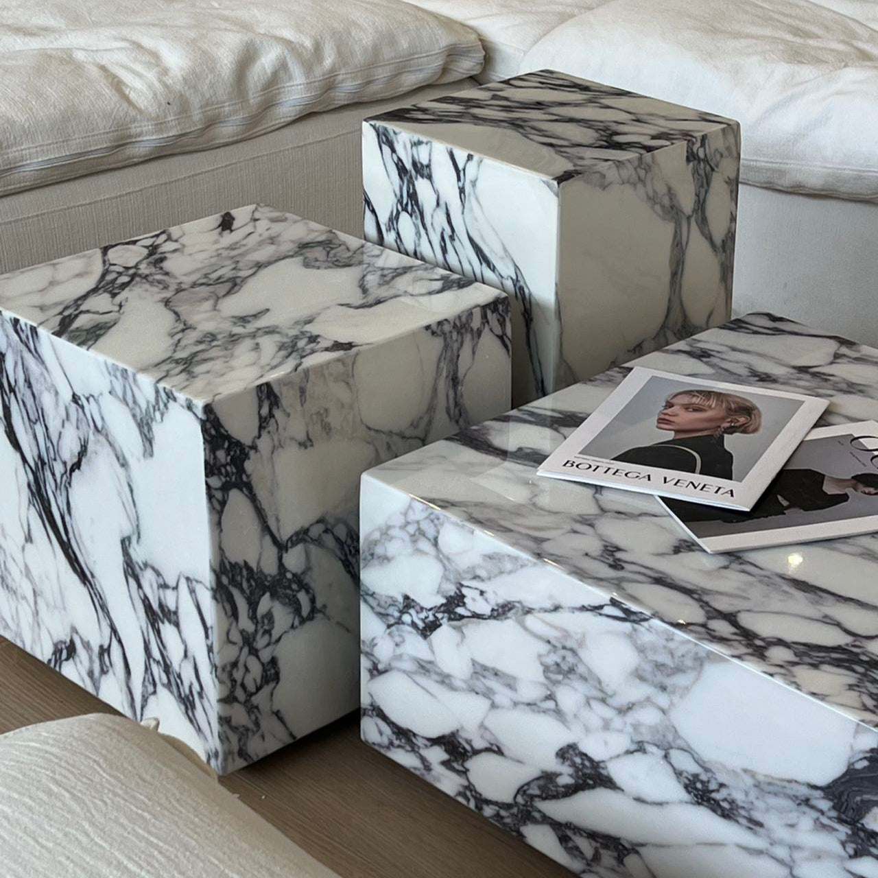 Bulgari Charm Coffee Table in white marble with bold dark veining shown in close-up detail beside cream modular sofa