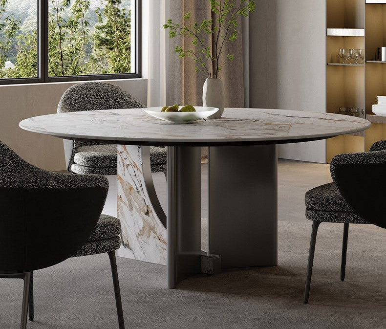 Celesti Elegance round dining table with marble-patterned sintered stone top and stainless steel base, styled with modern chairs beside a large window