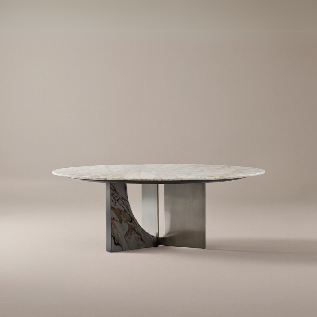 Celesti Elegance dining table featuring a round sintered stone top and sculptural stainless steel base with marble pattern accent in a neutral studio setting