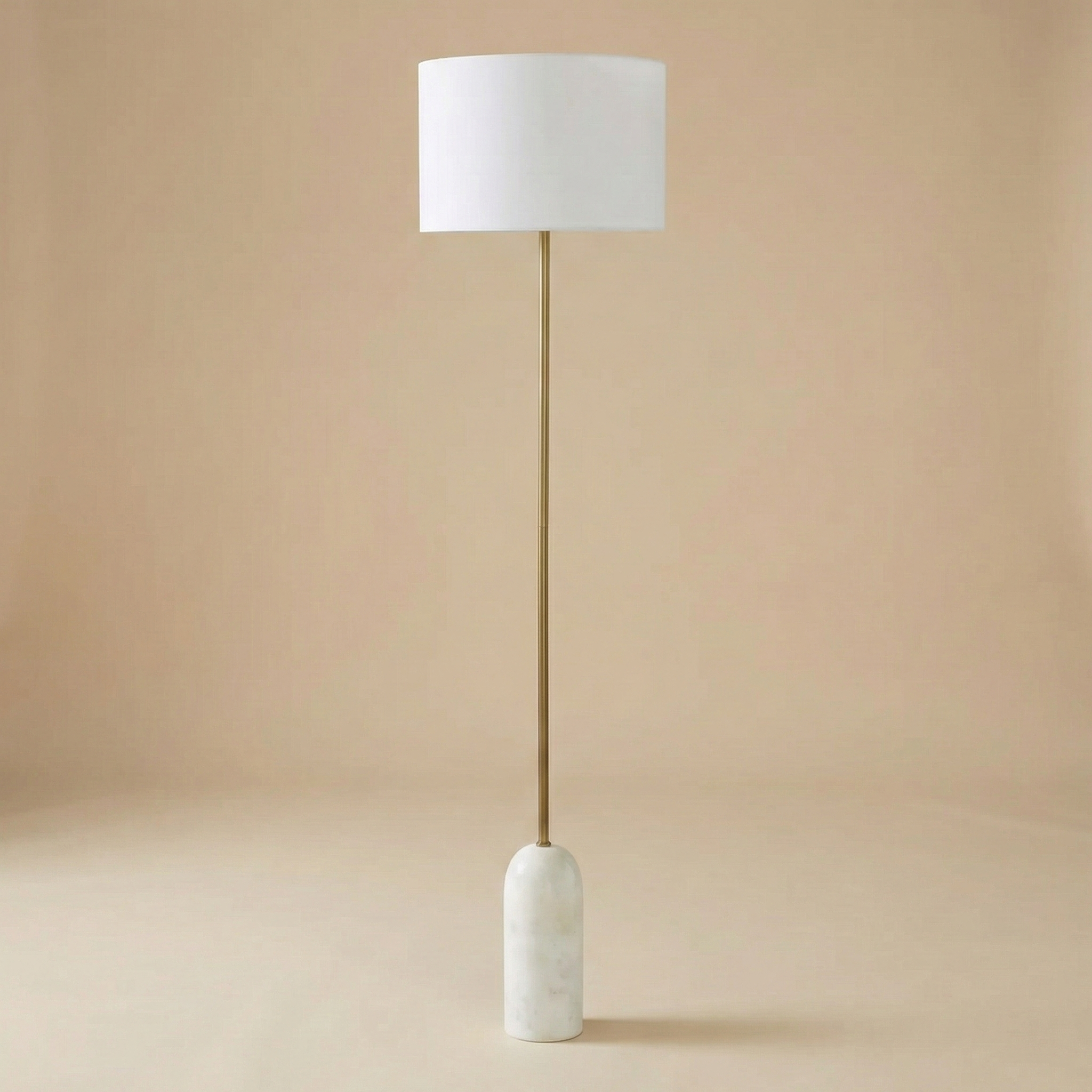 Celine floor lamp featuring a cylindrical white marble base, slender antique brass stem, and crisp white linen drum shade.