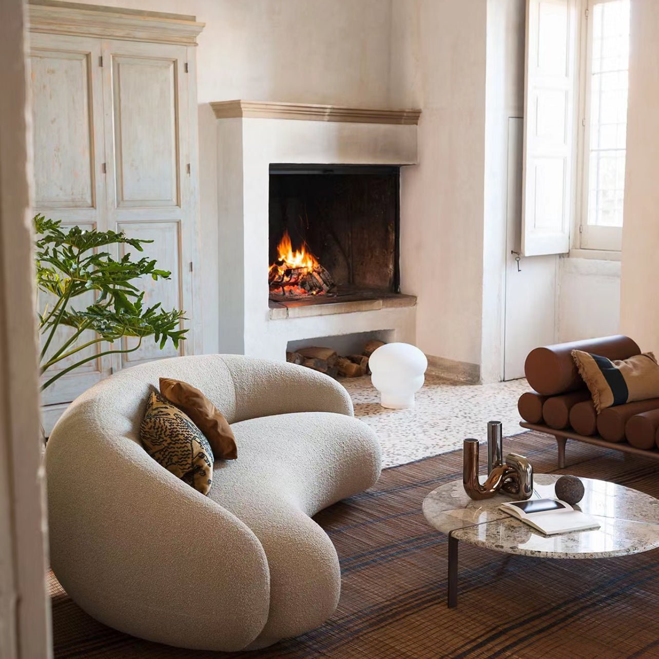 Contour Bliss Bouclé Sofa in white curved design beside fireplace and marble coffee table