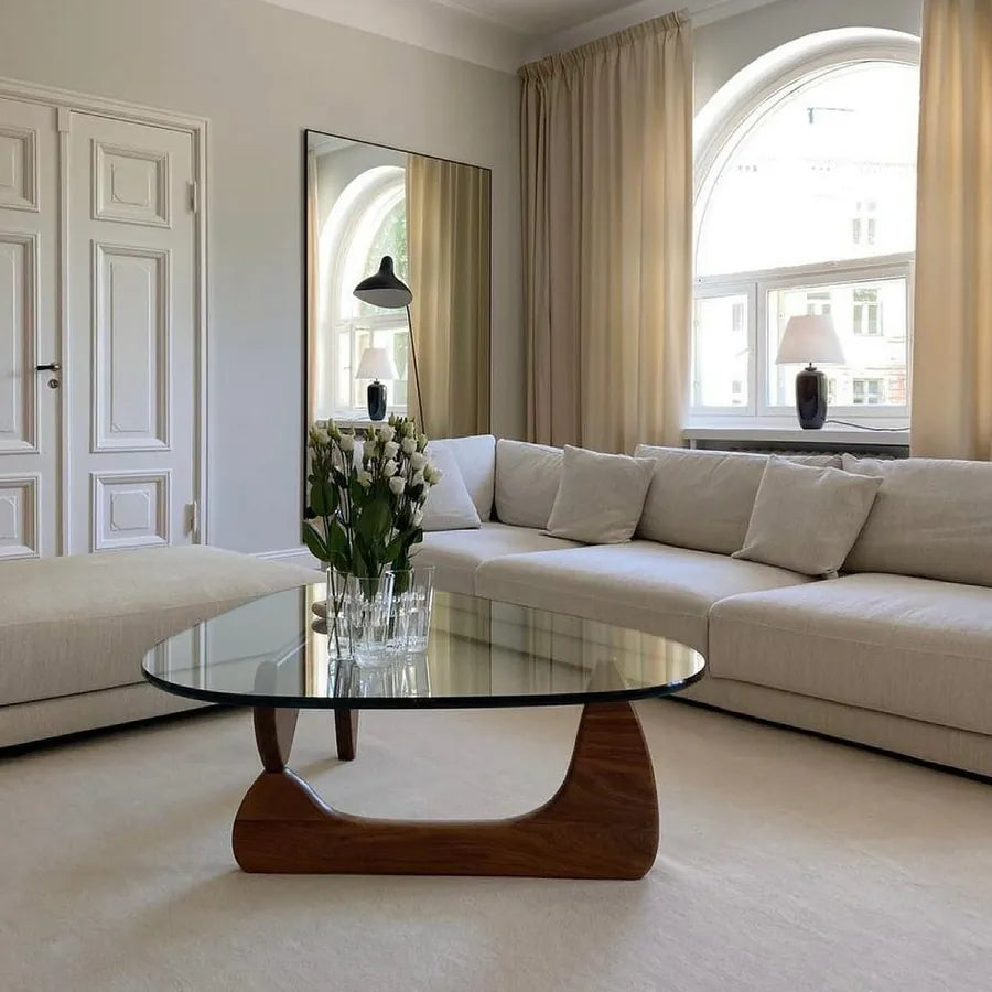 Contour Glass Coffee Table with round glass top and sculpted walnut base styled in a bright neutral living room