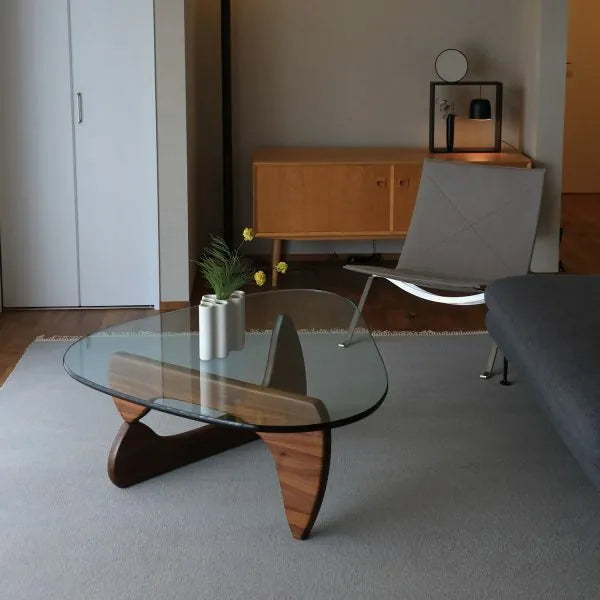 Contour Glass Coffee Table with walnut wood base and curved glass top in a minimalist living room setup