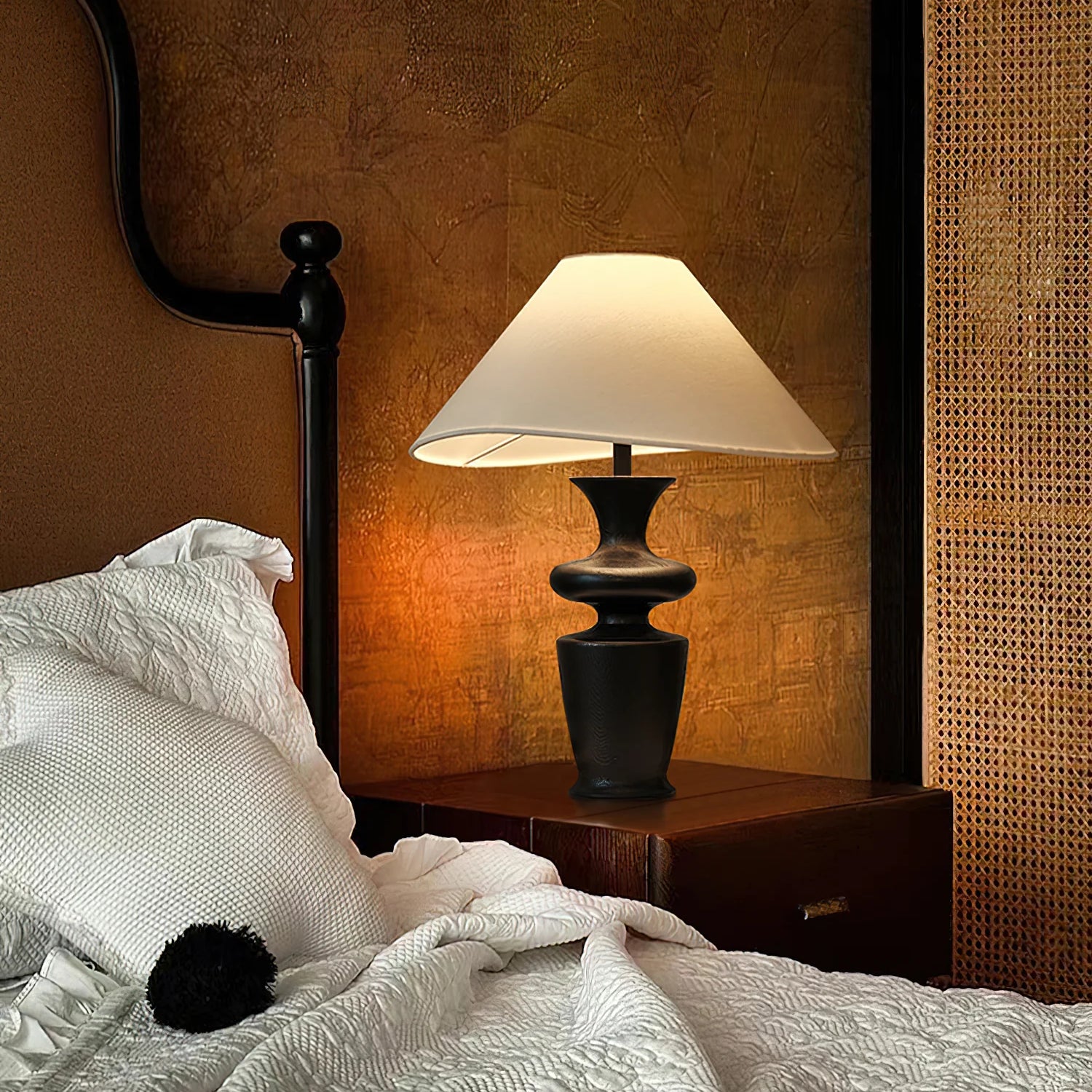Contour Table Lamp with black sculpted base and white shade on bedside table in warm cozy bedroom