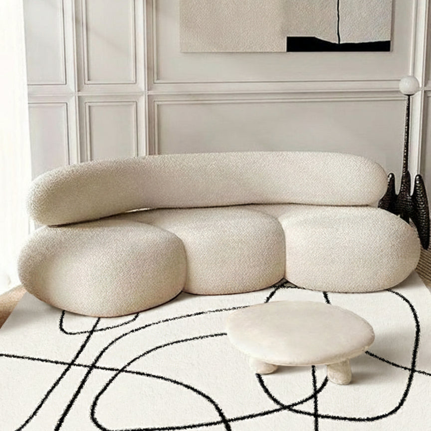 Eclipse Black and White Abstract Rug styled with a modern cream curved sofa and round low table in a bright living room