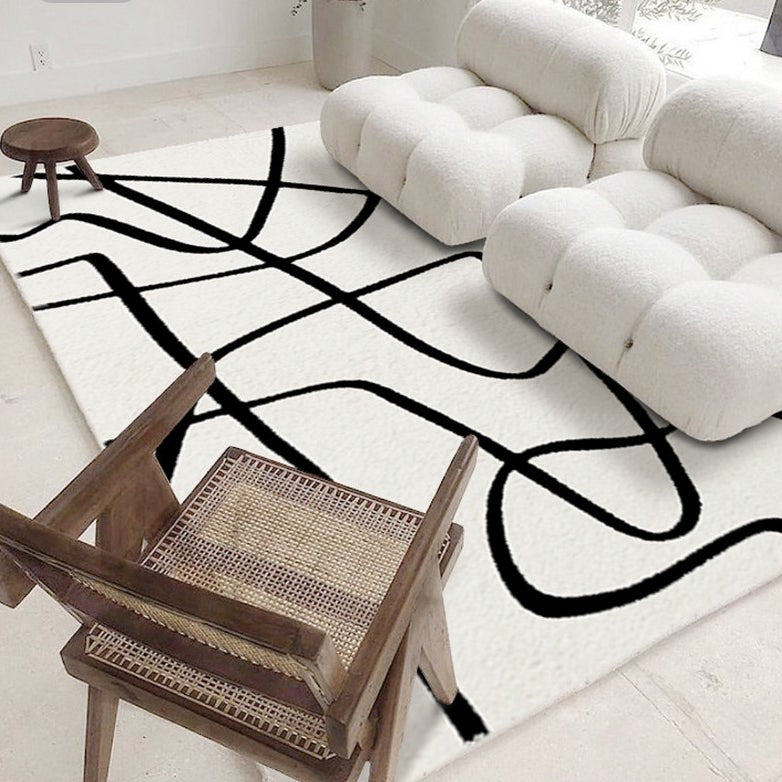 Eclipse Black and White Abstract Rug styled in a modern living room with white lounge chairs and a wooden accent chair