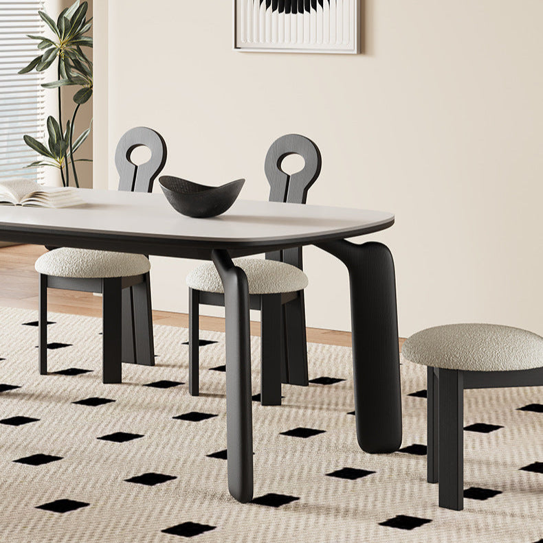 Side view of Eclipse Elegance dining table with sintered stone top and sculpted black wood legs paired with boucle dining chairs