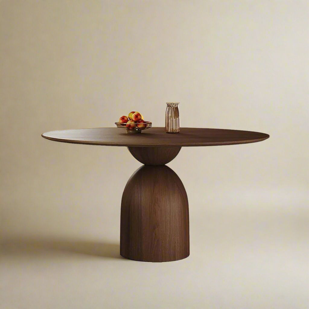 Evelyn Dining Table with round walnut top and sculptural pedestal base on beige studio background