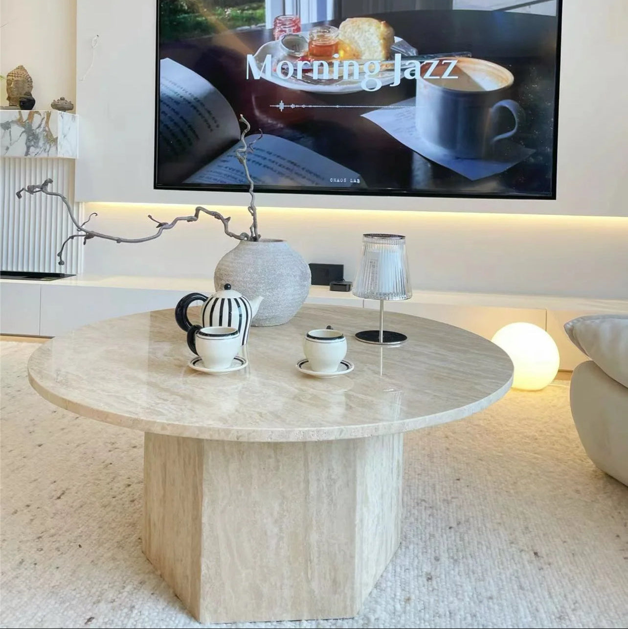 Harmony Travertine Coffee Table styled with striped teapot and cups in a cozy living room playing Morning Jazz on TV