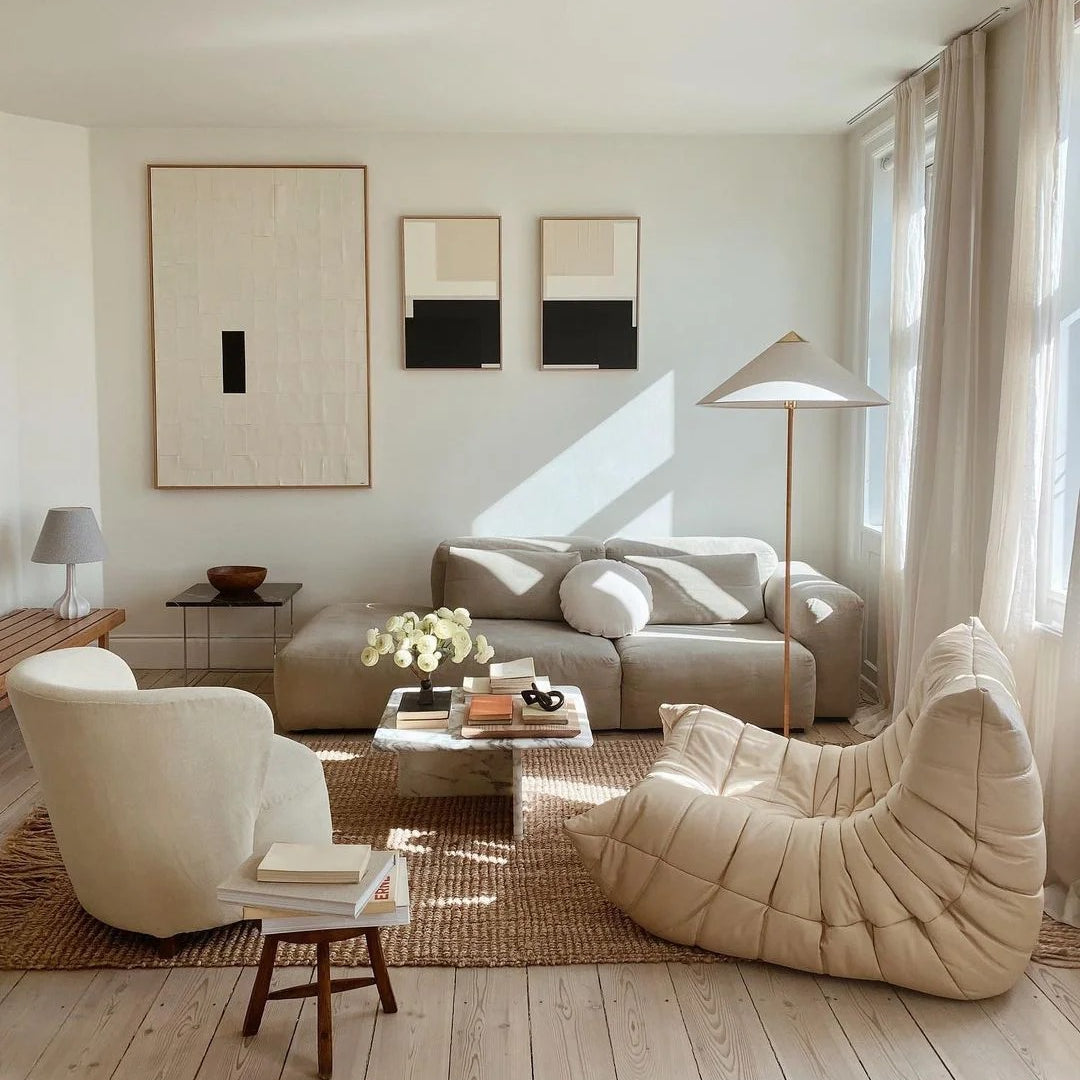 Horizon Shade Floor Lamp with brass base and conical shade in a bright neutral living room with beige sofa and lounge chair