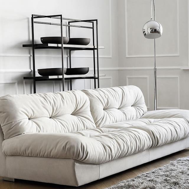 Italian-style Cloud Sofa in cream ultra suede with deep tufted cushions, shown in a modern living room with black shelving and floor lamp