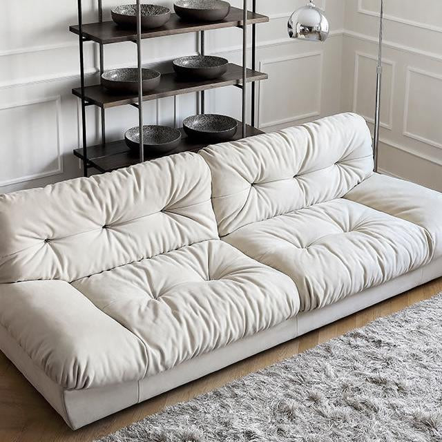 Italian-style Cloud Sofa in cream ultra suede with deep tufted seat and back cushions, styled in a modern living room with shag rug and shelving