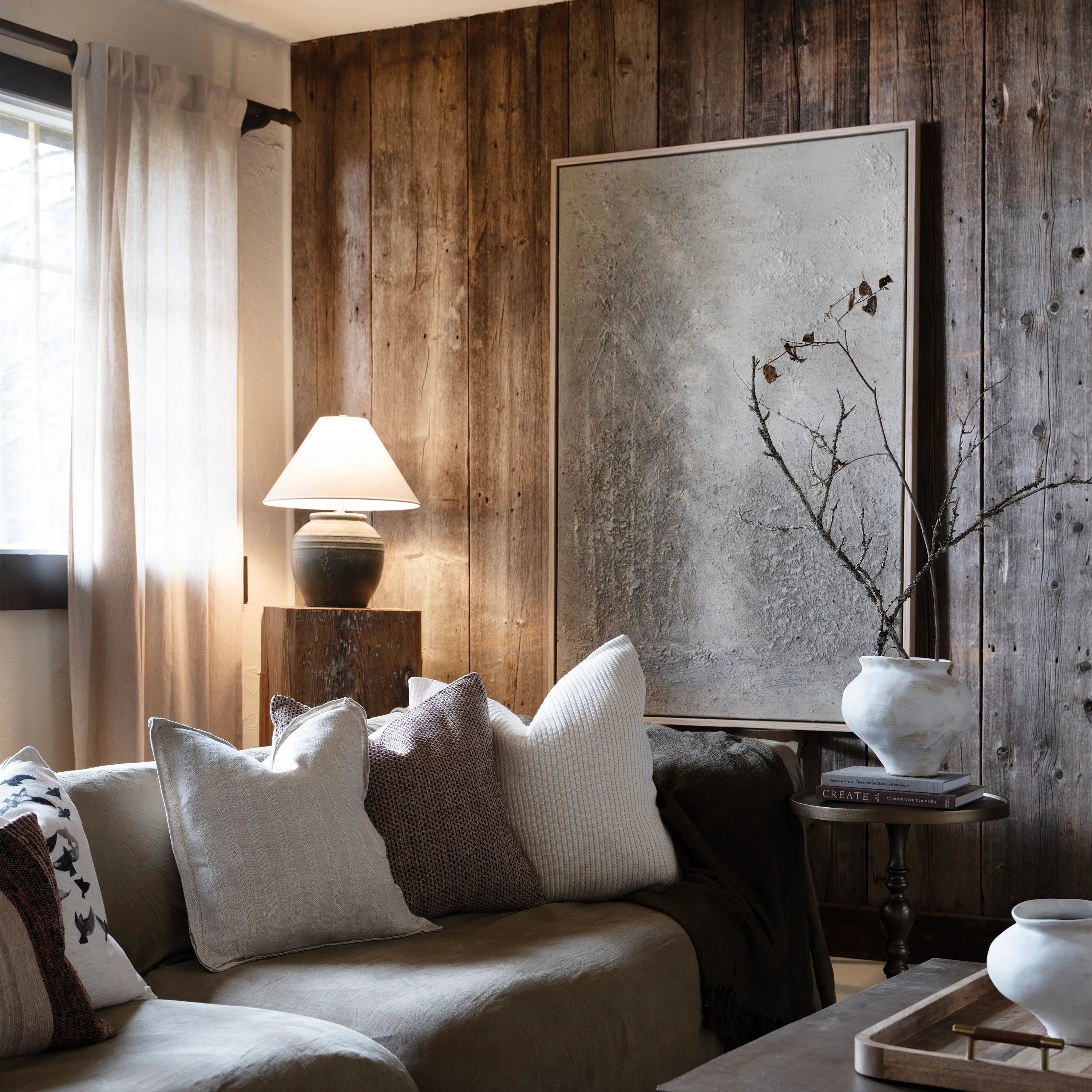 Keros Vase styled on a wooden side table in a cozy living room with neutral pillows and textured wall art