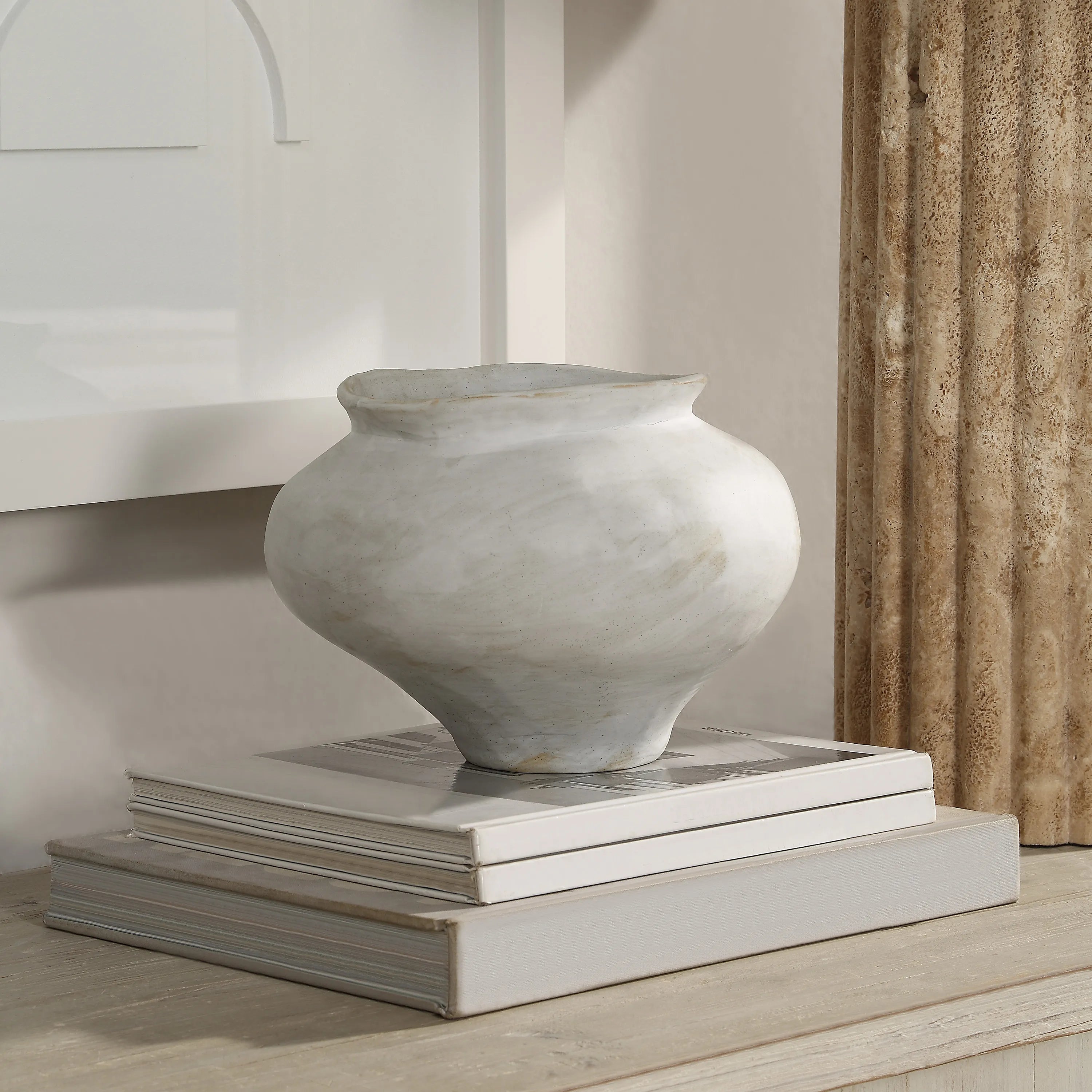 Leros Vase styled on stacked neutral books beside textured column and framed wall art