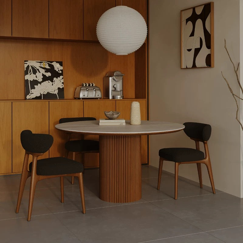 Lucia Dining Table styled in a cozy dining nook with warm wood cabinets, paper lantern light, and dark fabric chairs