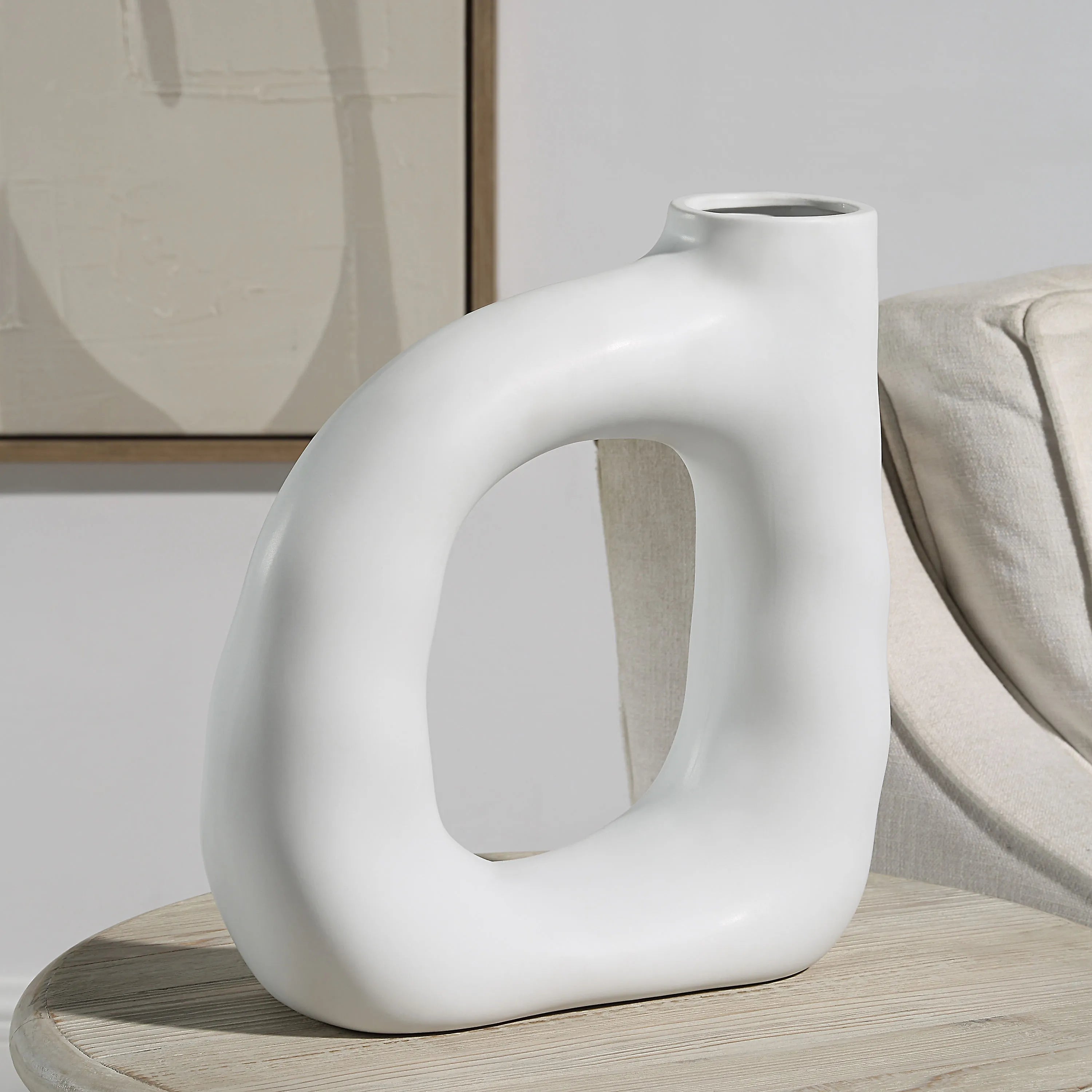 Lunara Vase in matte white displayed on a neutral table beside a beige chair and modern artwork