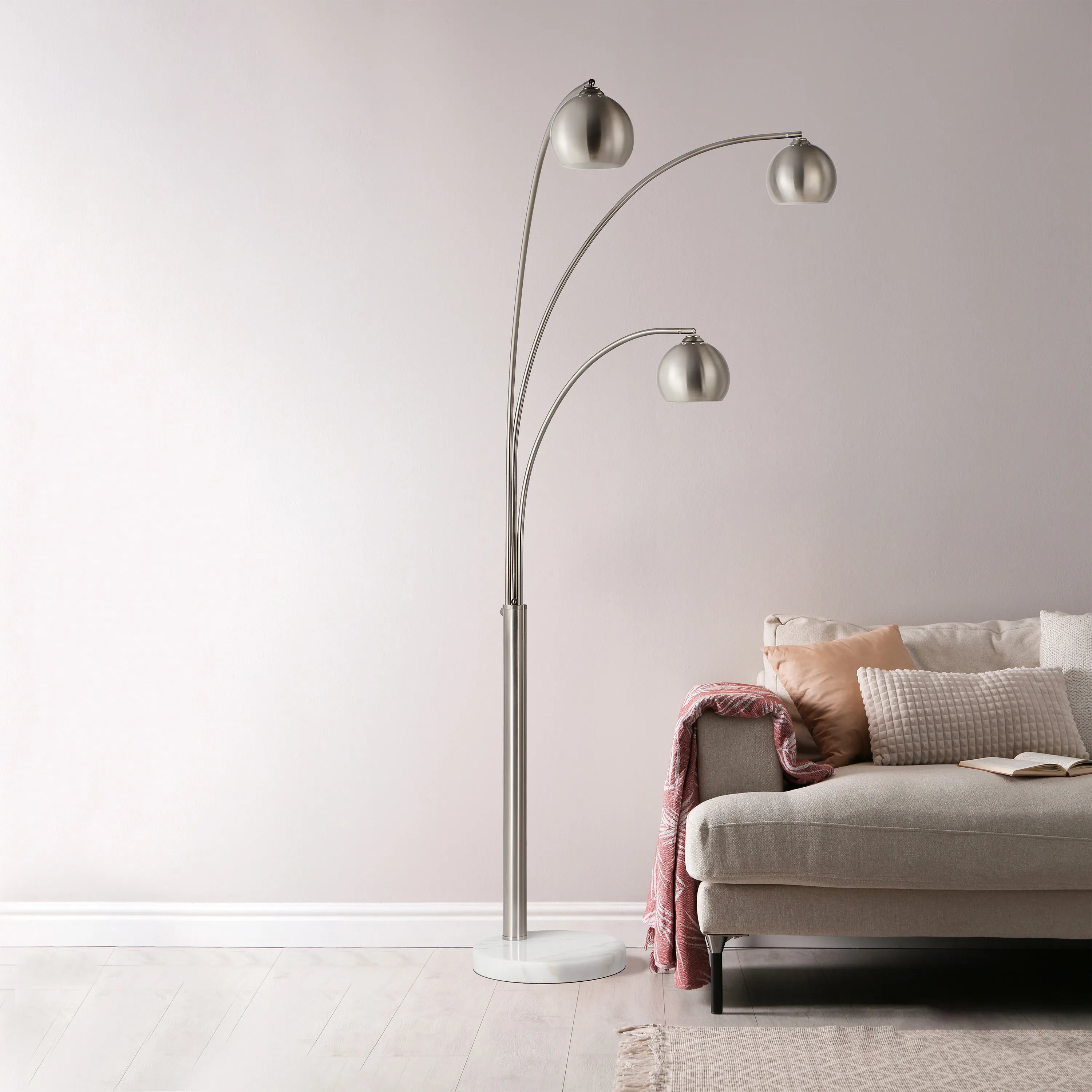 Lyra Arc Floor Lamp with triple curved arms beside beige sofa in modern living room
