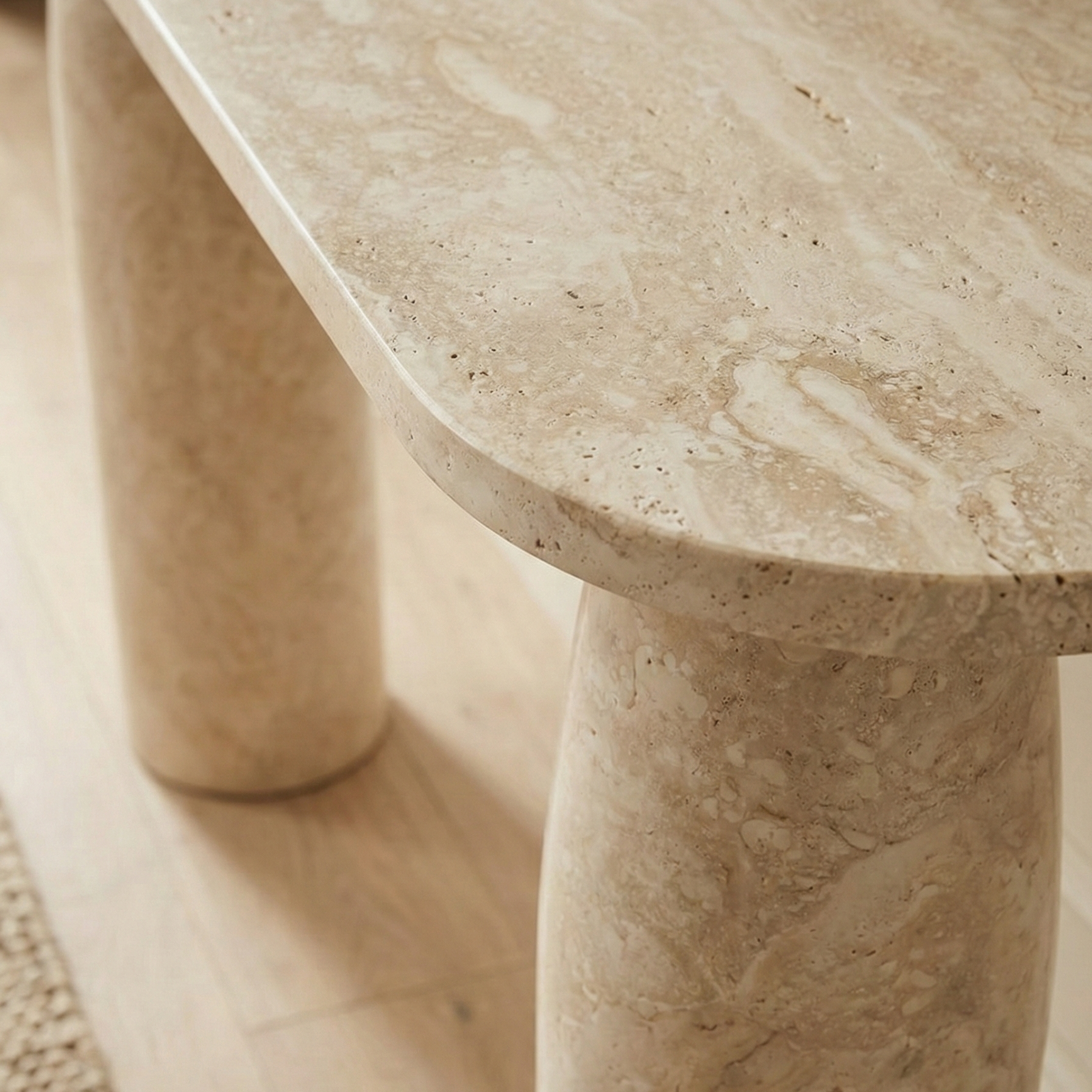 Close up detail of the Maelis console table showing the natural pitting, veining, and raw texture of the beige travertine stone surface.