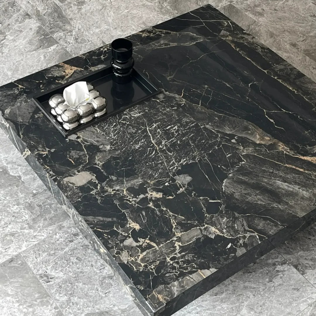 A luxurious black marble coffee table with a sleek, modern design. It features a built-in tray and offers a stylish centerpiece for any living space.