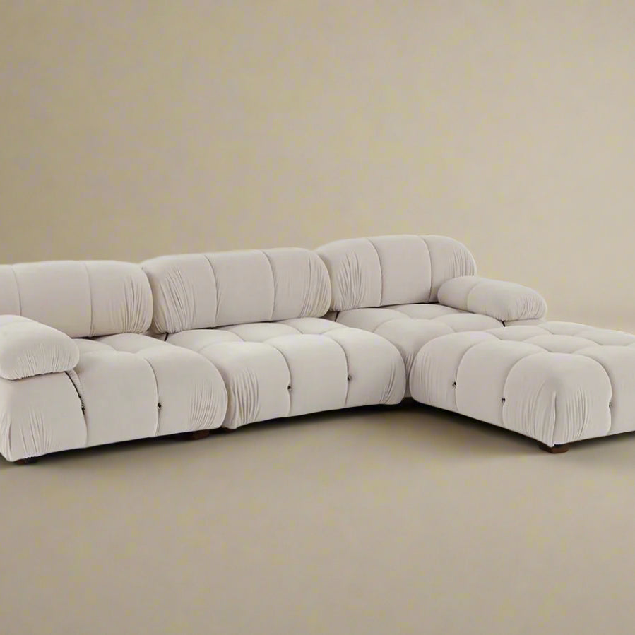 Mario Bellini Sofa in white bouclé fabric arranged in an L-shaped sectional with deep tufting and plush cushions on beige background