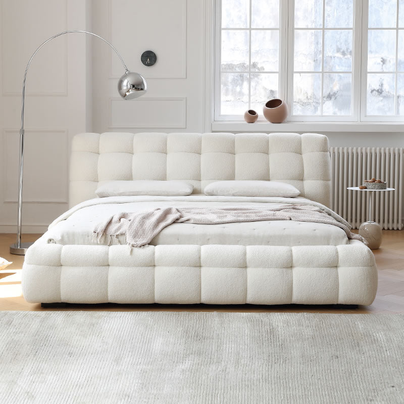 Marshmallow Puff Bed in ivory boucle fabric with tufted frame and pillows styled in a sunlit modern bedroom with floor lamp