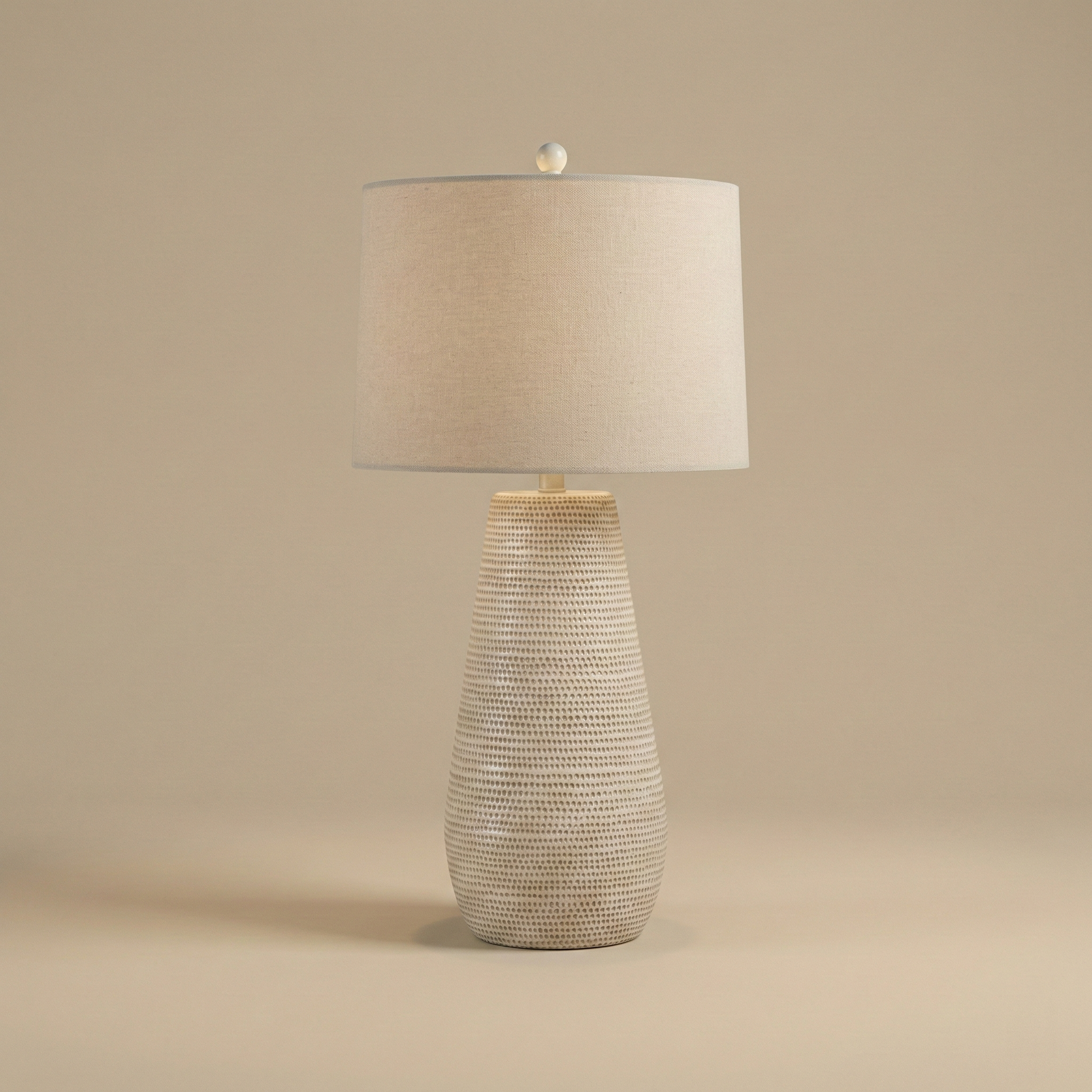Table lamp with textured base and beige shade on a beige background