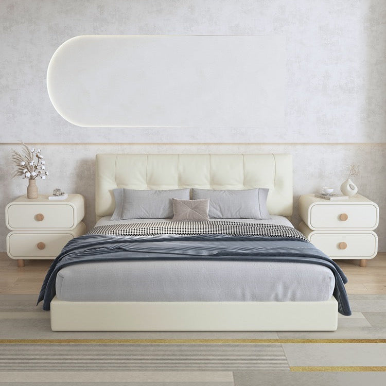 Two cream Milan modern rounded nightstands styled on either side of a white tufted bed in a bright, contemporary bedroom.