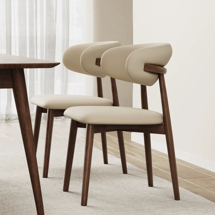 Two Modern Leather Ash Wood Dining Side Chairs shown in a bright dining room, featuring curved upholstery and solid ash wood legs