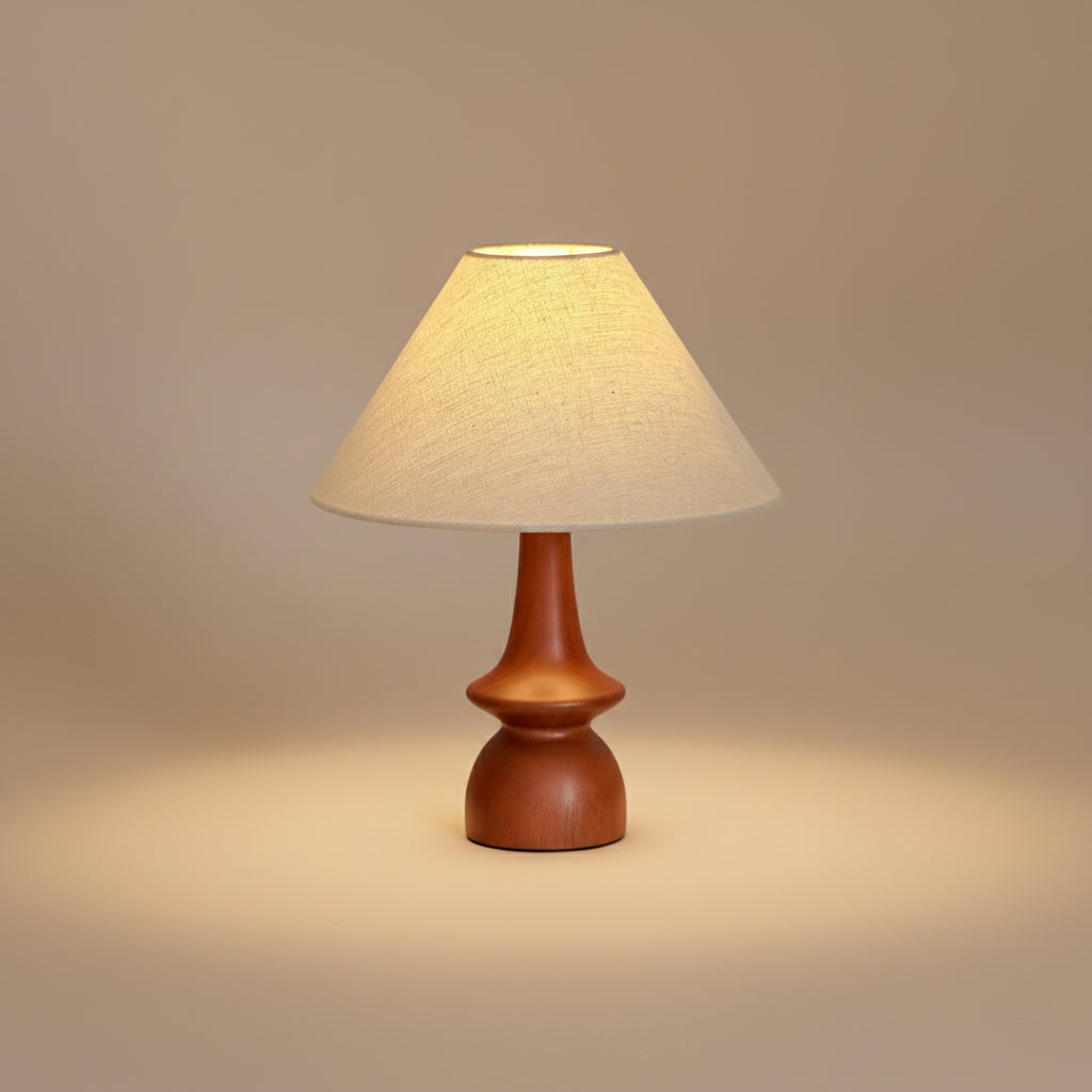 Olivia Table Lamp with wooden base and fabric shade glowing warmly in a beige studio setting