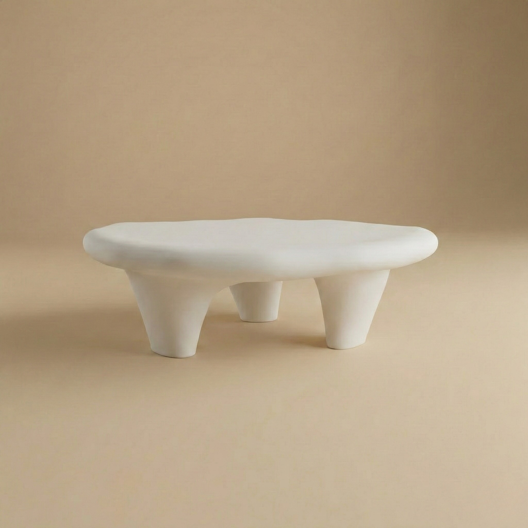 Pebble coffee table in white featuring a smooth organic shape and chunky tripod legs with a plaster-style finish.