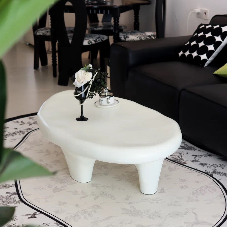 Pebble Coffee Table in matte white finish styled beside black leather sofa with patterned rug and elegant modern decor