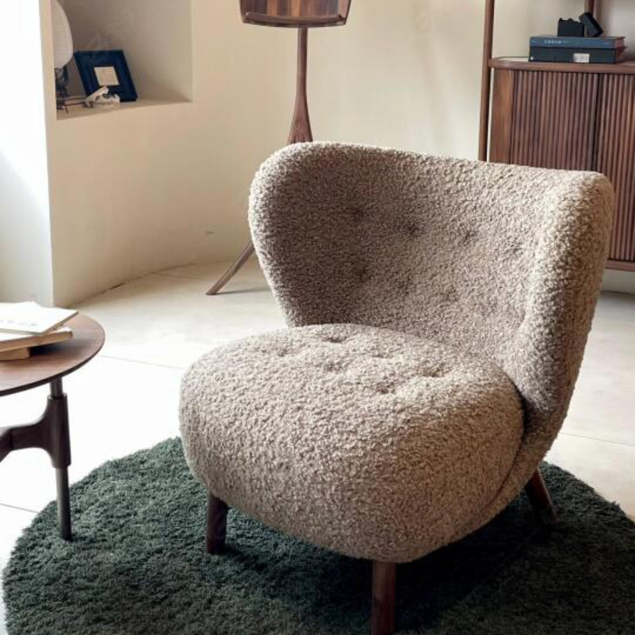 Petra Accent Chair in brown boucle fabric with wooden legs styled in a cozy living room corner on a green rug