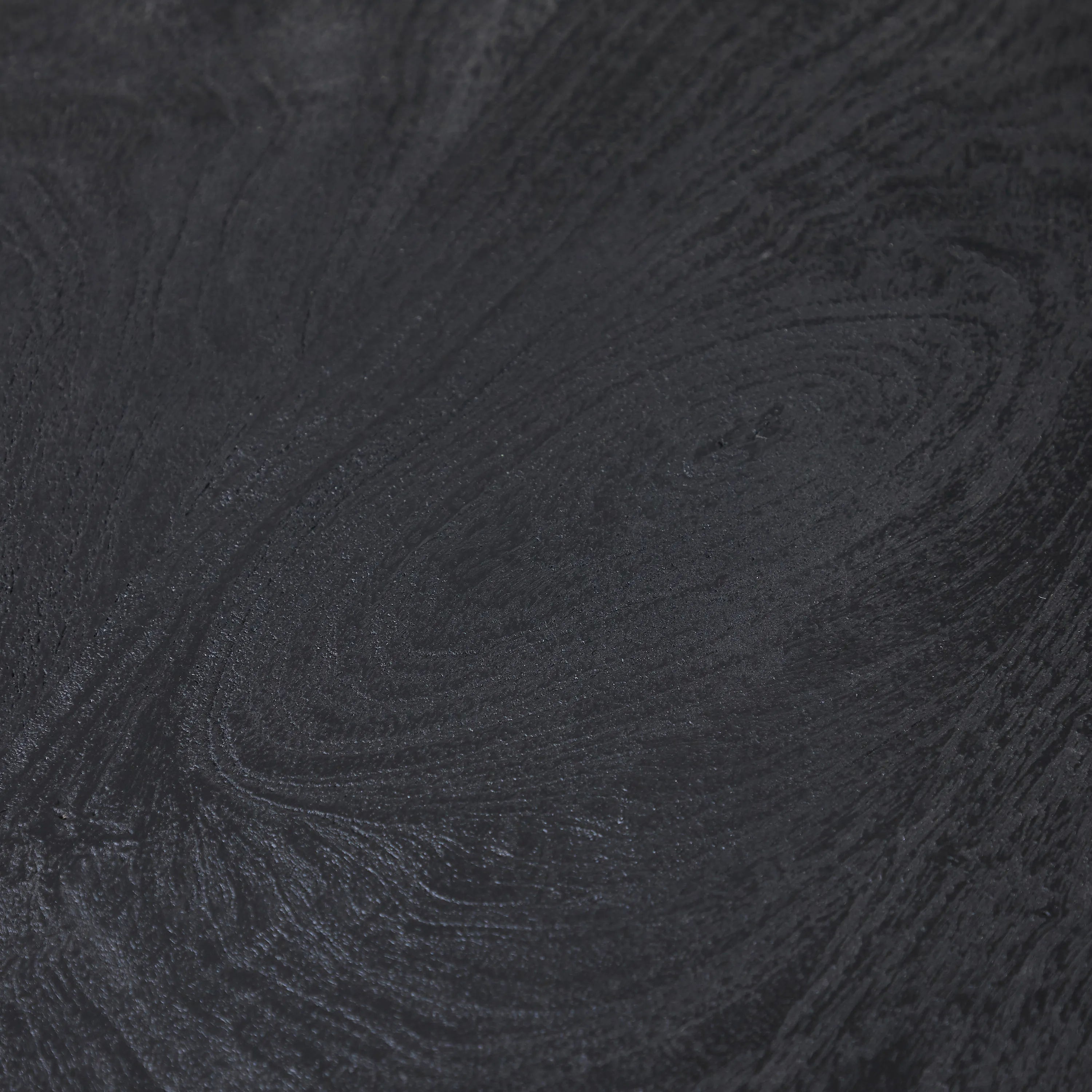 Macro detail of the Ryn side table showing the rich wood grain texture visible through the matte black finish.