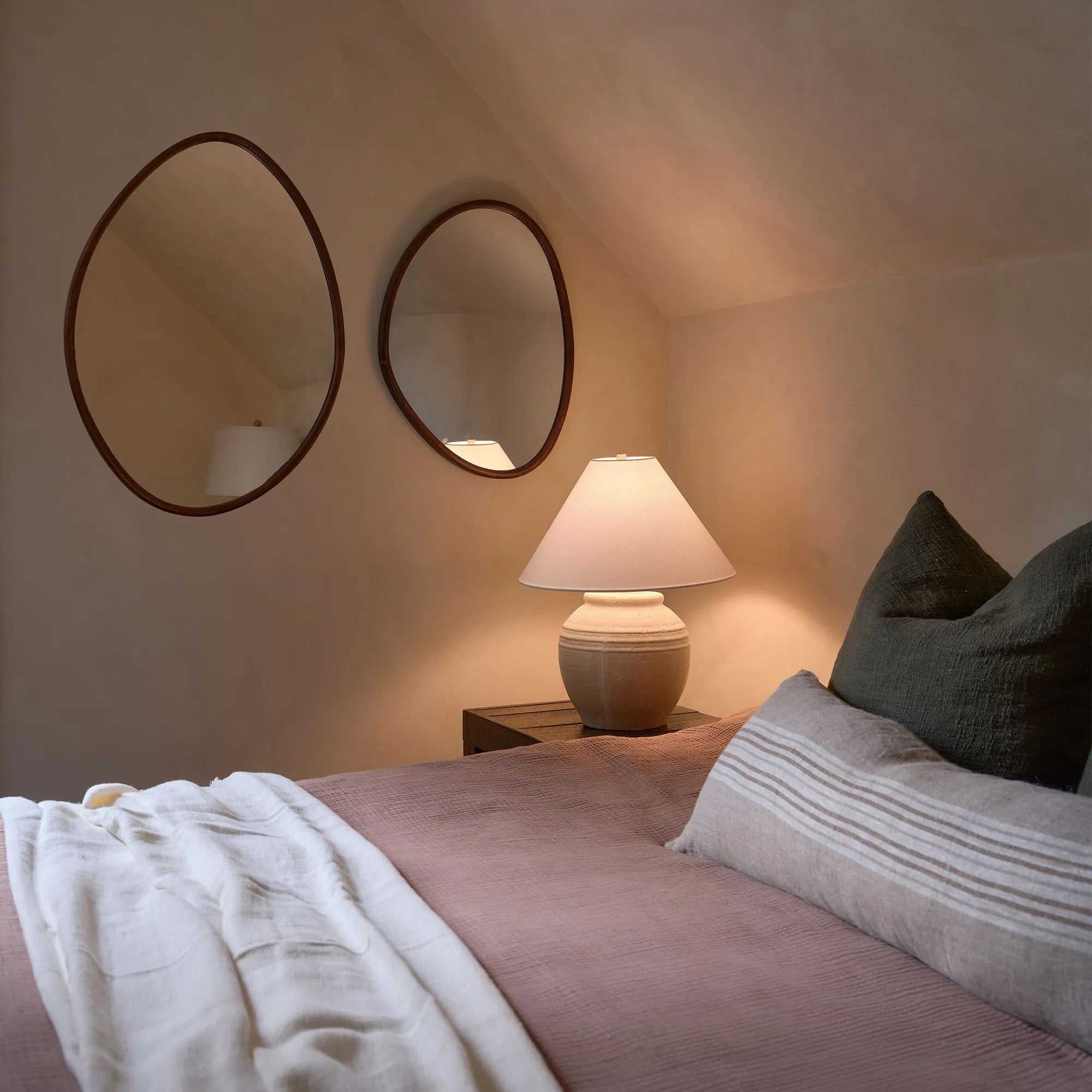 Solstice Wall Mirror Set styled above a bedside table with a warm lamp in a cozy bedroom