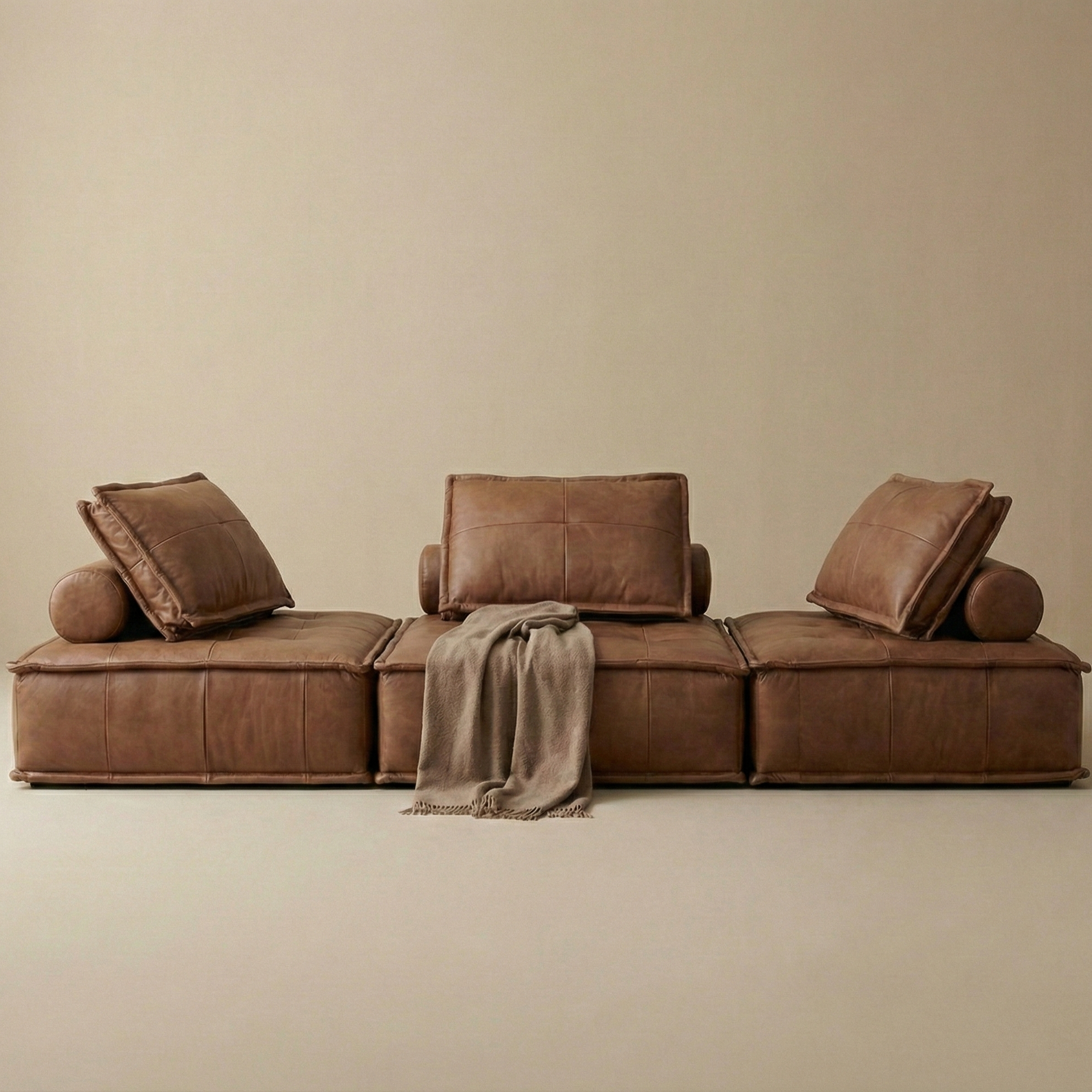 Brown sectional sofa with cushions and a blanket on a beige background