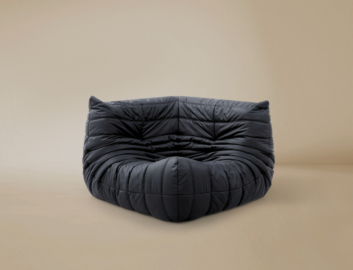 Dark grey TOGO Lounger corner chair showing deep tufted folds and low profile floor seating design.