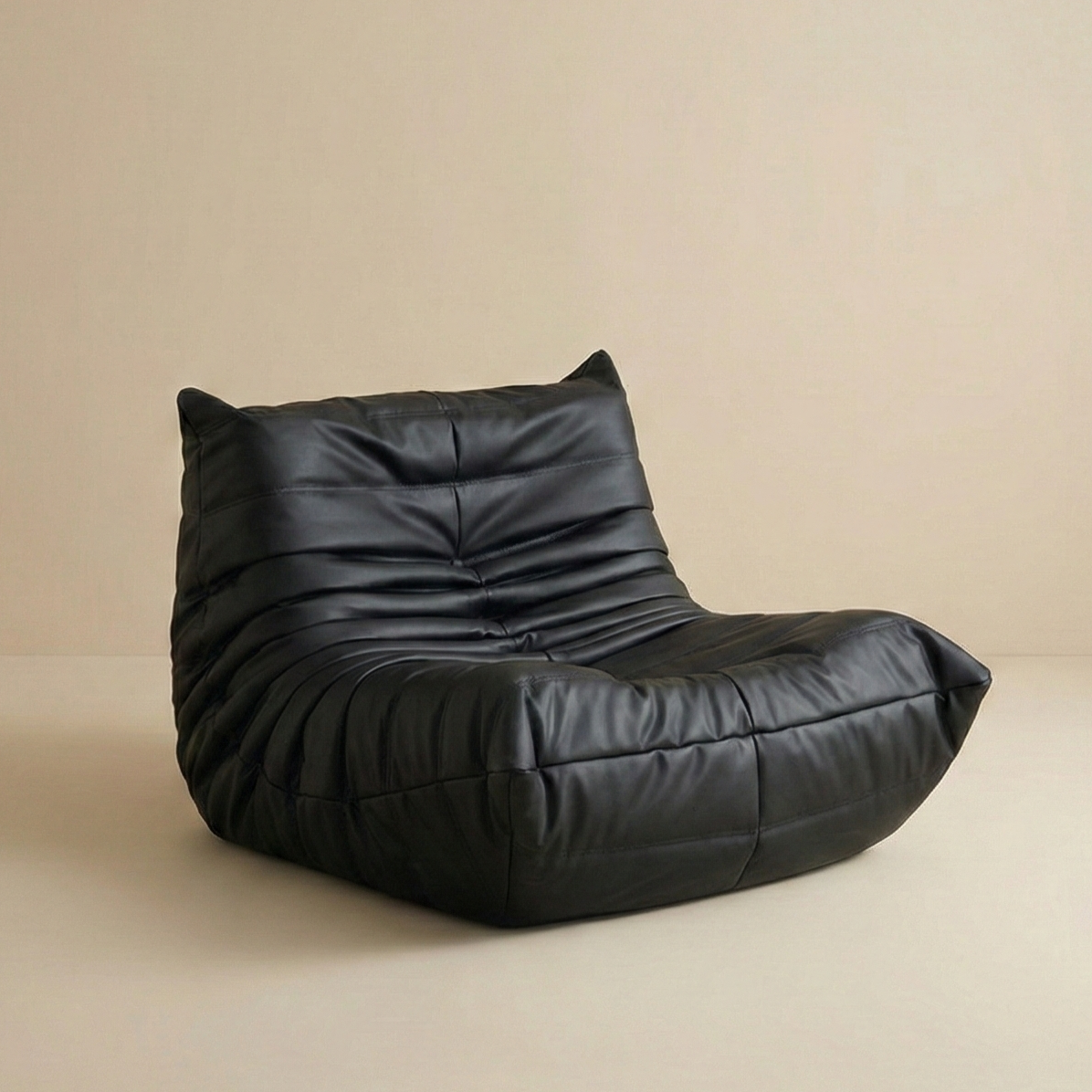 Black leather TOGO Lounger chair featuring classic gathered seams and durable low floor seating design.