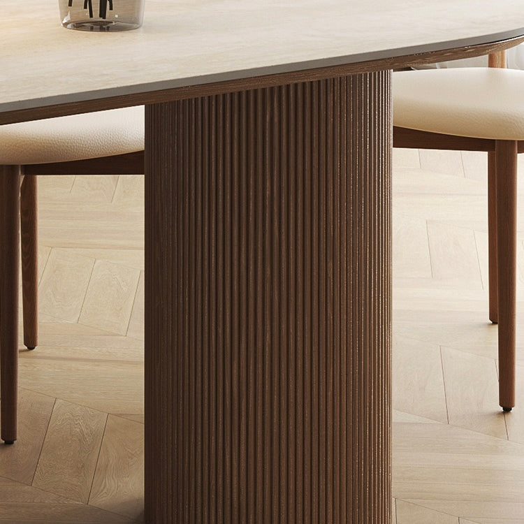 Close-up of travertine sintered stone dining table with fluted solid wood base on light oak floor