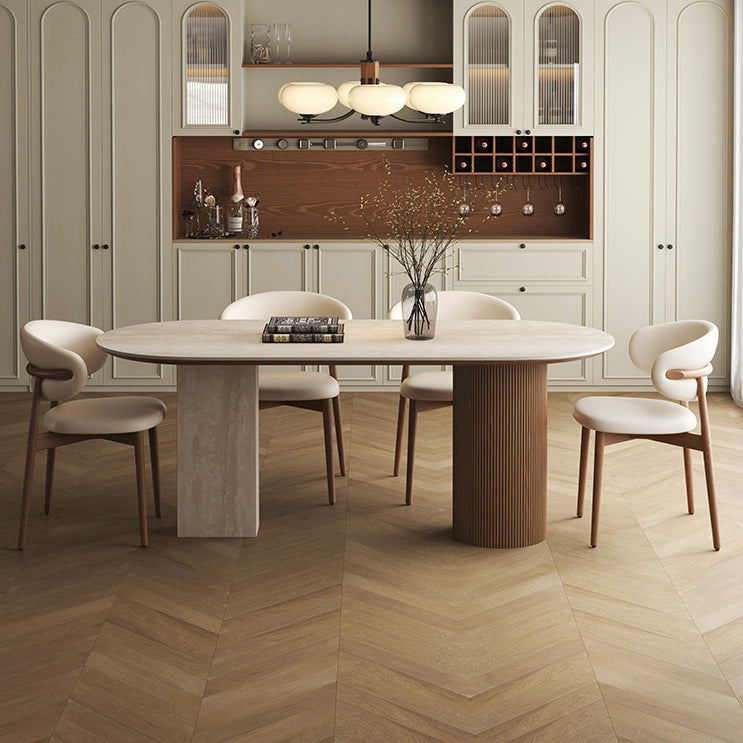 Travertine sintered stone dining table with wood base styled with cream chairs in modern kitchen interior